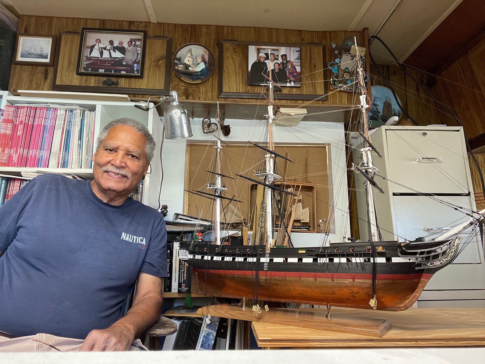 George Lowery smiling beside his scratch-built USS Constitution model in his studio